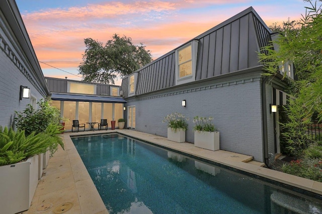 5 Green Ln, Austin, TX 78703 - back of property featuring an outdoor pool, brick siding, board and batten siding, a patio, and a sunroom
