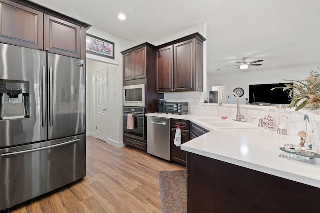 1004 Oaklands Dr, Round Rock, TX 78681 - kitchen featuring appliances with stainless steel finishes, dark brown cabinets, light countertops, light wood finished floors, and tasteful backsplash