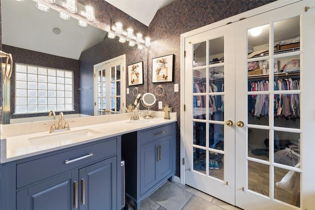 1004 Oaklands Dr, Round Rock, TX 78681 - bathroom featuring wallpapered walls, french doors, vaulted ceiling, double vanity, and a spacious closet