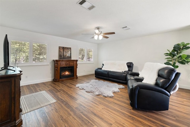 1004 Oaklands Dr, Round Rock, TX 78681 - living room with wood finished floors, ceiling fan, and a lit fireplace