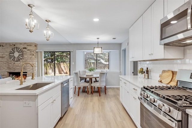 11309 Timbrook Trl, Austin, TX 78750 - kitchen with stainless steel appliances, light countertops, backsplash, a stone fireplace, and light wood-style flooring