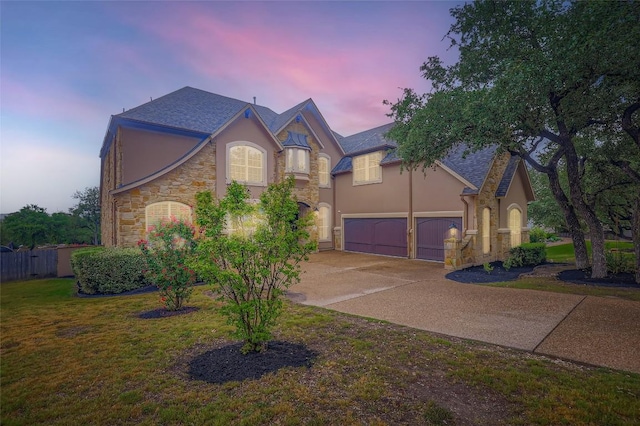 217 Emerald Ridge Dr, Austin, TX 78732 - view of front of house featuring stucco siding, stone siding, driveway, a lawn, and an attached garage