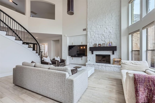 217 Emerald Ridge Dr, Austin, TX 78732 - living area featuring a towering ceiling, stairway, light wood-style floors, and a fireplace