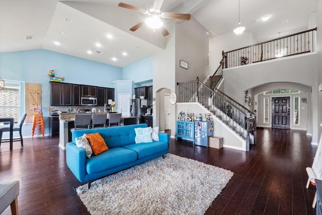 137 Paul Azinger Dr, Round Rock, TX 78664 - living room with high vaulted ceiling, arched walkways, stairs, a ceiling fan, and dark wood-style flooring