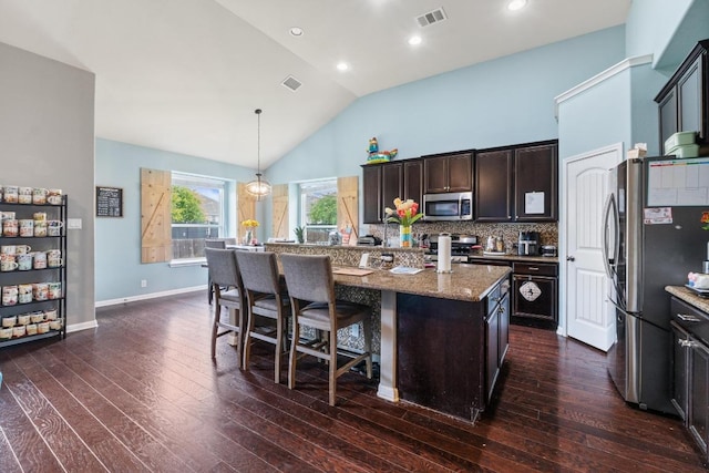 137 Paul Azinger Dr, Round Rock, TX 78664 - kitchen with stainless steel appliances, light stone countertops, a kitchen island, a breakfast bar, and dark wood-style floors