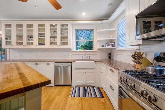 903 E 14th St, Austin, TX 78702 - kitchen with stainless steel appliances, butcher block counters, white cabinetry, light wood finished floors, and tasteful backsplash