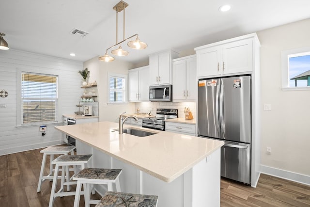 162 La Concha Blvd Unit 10, Port Aransas, TX 78373 - kitchen with appliances with stainless steel finishes, dark wood-style floors, white cabinetry, a center island with sink, and a kitchen bar