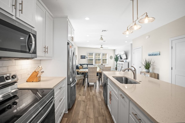 162 La Concha Blvd Unit 10, Port Aransas, TX 78373 - kitchen featuring stainless steel appliances, dark wood finished floors, decorative backsplash, open floor plan, and a ceiling fan