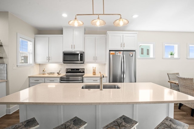 162 La Concha Blvd Unit 10, Port Aransas, TX 78373 - kitchen with stainless steel appliances, backsplash, white cabinetry, wood finished floors, and a kitchen island with sink