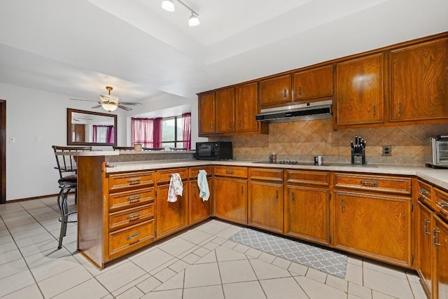 1303 Creekview Dr, Round Rock, TX 78681 - kitchen featuring under cabinet range hood, a peninsula, black appliances, and tasteful backsplash