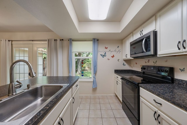 236 Lodestone Cir, Cedar Park, TX 78613 - kitchen with stainless steel microwave, black range with electric cooktop, dark countertops, a tray ceiling, and light tile patterned floors