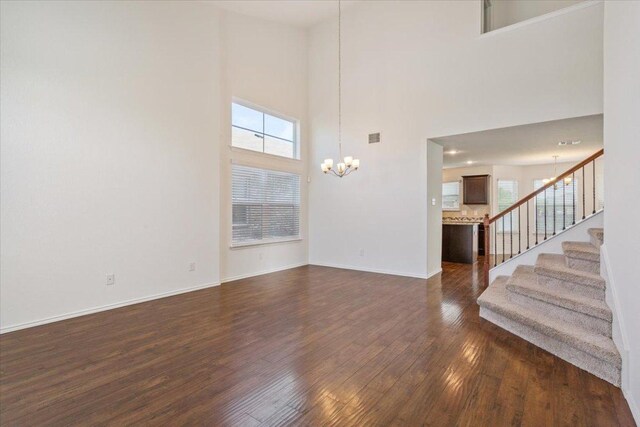 3211 Malmaison Rd, Killeen, TX 76542 - unfurnished living room with a chandelier, dark wood-style floors, a towering ceiling, healthy amount of natural light, and stairway