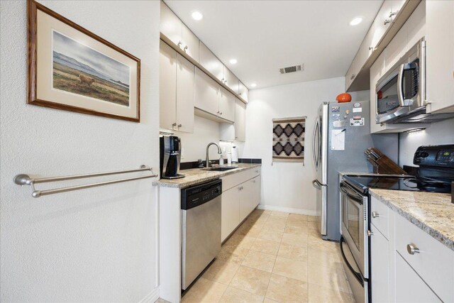1801 Lavaca St Unit 9J, Austin, TX 78701 - kitchen with stainless steel appliances, white cabinets, recessed lighting, and light tile patterned floors