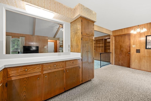 1411 Shenandoah Dr, Cedar Park, TX 78613 - kitchen featuring wood walls, light carpet, light countertops, brown cabinets, and a chandelier