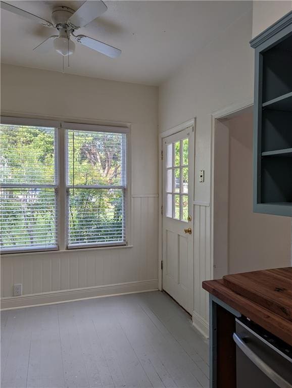 308 Taylor Rd, Elgin, TX 78621 - doorway to outside featuring a wainscoted wall, light wood-type flooring, a ceiling fan, and plenty of natural light