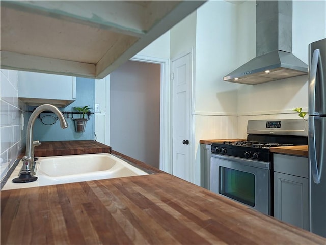 308 Taylor Rd, Elgin, TX 78621 - kitchen featuring wall chimney range hood, wood counters, appliances with stainless steel finishes, and wainscoting