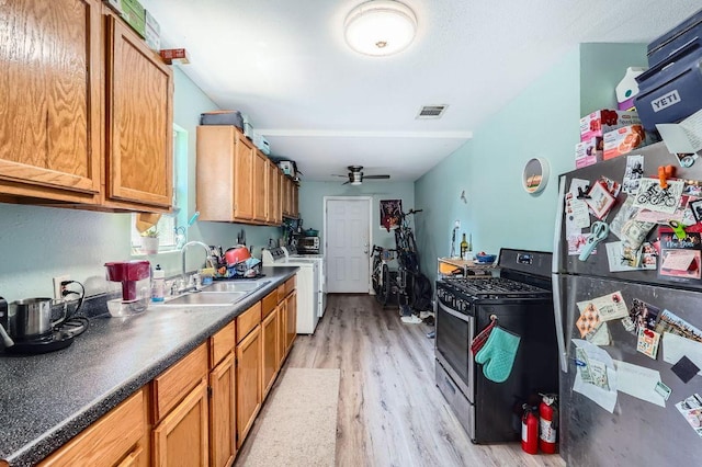5605 Tura Ln, Austin, TX 78721 - kitchen featuring stainless steel appliances, washer / clothes dryer, ceiling fan, light wood-style flooring, and brown cabinets