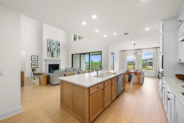 8405 Ambergill Ct, Austin, TX 78744 - kitchen featuring dishwasher, a fireplace, recessed lighting, a center island with sink, and light wood-style floors