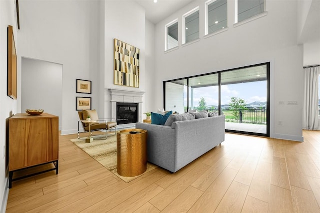 8405 Ambergill Ct, Austin, TX 78744 - living area featuring a towering ceiling, light wood-style flooring, a glass covered fireplace, and healthy amount of natural light