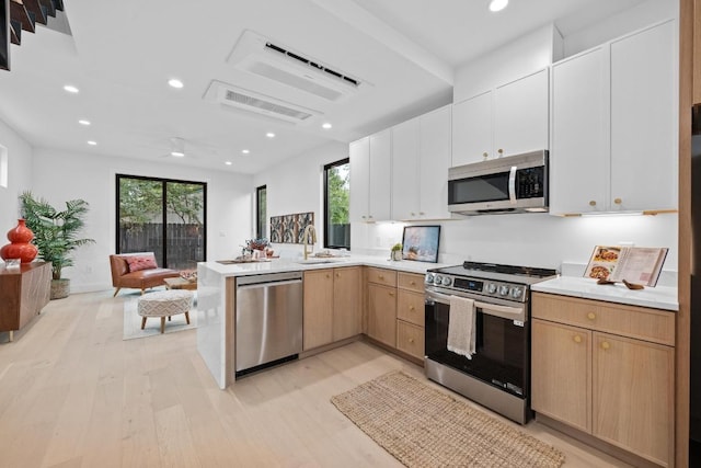 4428 Jinx Ave Unit 2, Austin, TX 78745 - kitchen featuring appliances with stainless steel finishes, open floor plan, light wood finished floors, a peninsula, and light countertops