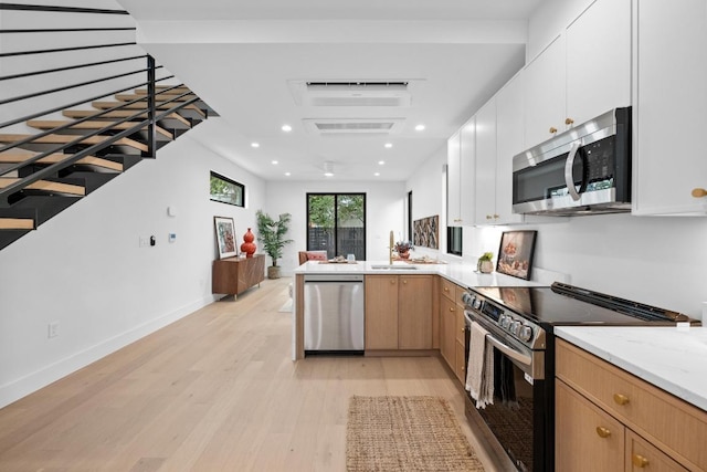 4428 Jinx Ave Unit 2, Austin, TX 78745 - kitchen with stainless steel appliances, light wood-style flooring, a peninsula, recessed lighting, and white cabinetry