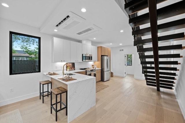 4428 Jinx Ave Unit 2, Austin, TX 78745 - kitchen featuring appliances with stainless steel finishes, a kitchen breakfast bar, light wood-style flooring, a peninsula, and recessed lighting