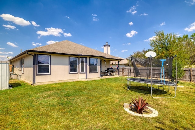 203 Endeavour, Kyle, TX 78640 - back of house featuring a trampoline, a fenced backyard, a chimney, and a patio area