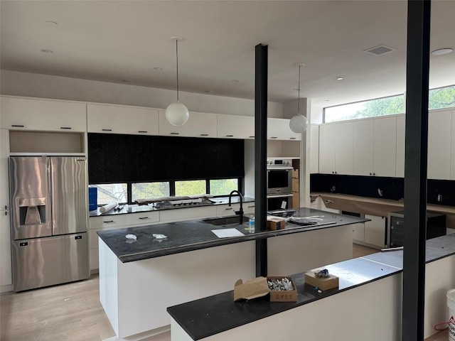 1603 Chelsea Ln Unit 1, Austin, TX 78704 - kitchen with stainless steel appliances, dark countertops, white cabinetry, a center island with sink, and modern cabinets