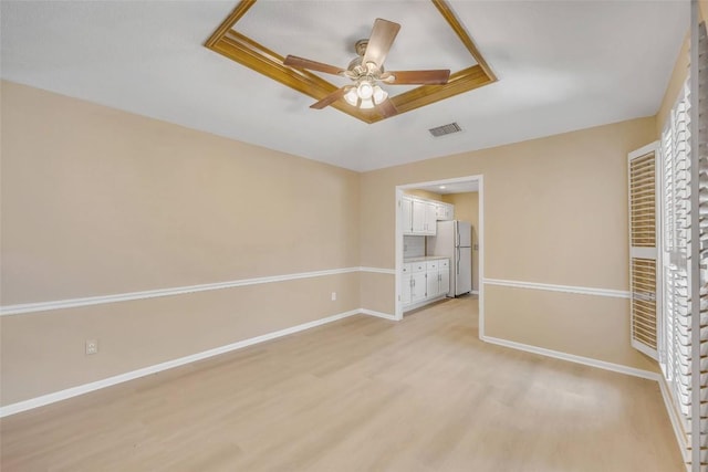 10007 Brantley Bnd, Austin, TX 78748 - unfurnished bedroom featuring freestanding refrigerator, light wood-style floors, a tray ceiling, ensuite bathroom, and a ceiling fan
