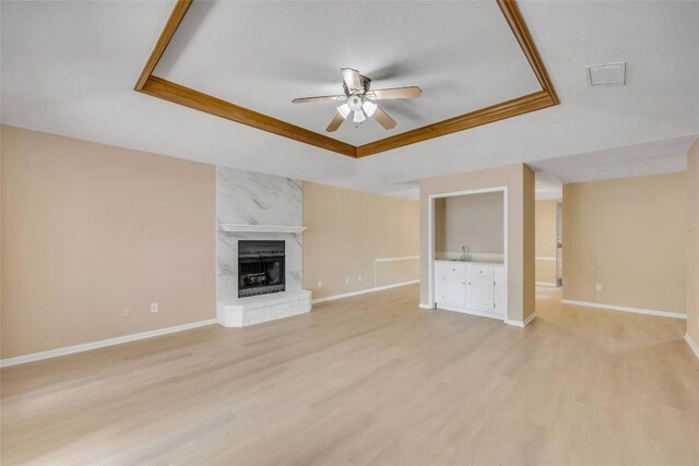 10007 Brantley Bnd, Austin, TX 78748 - unfurnished living room with a raised ceiling, a ceiling fan, light wood-style flooring, and a high end fireplace