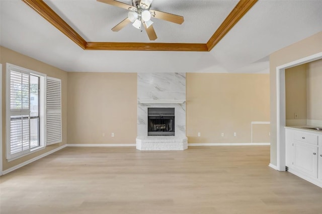 10007 Brantley Bnd, Austin, TX 78748 - unfurnished living room with a tray ceiling, light wood-style flooring, a fireplace, a ceiling fan, and crown molding