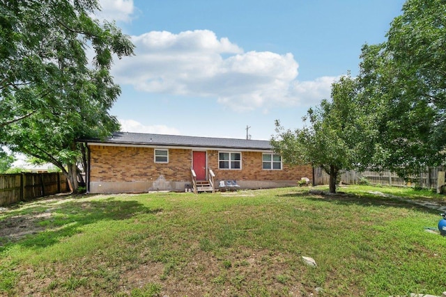 709 Harvey Ave, Burnet, TX 78611 - rear view of property featuring entry steps, brick siding, and a fenced backyard
