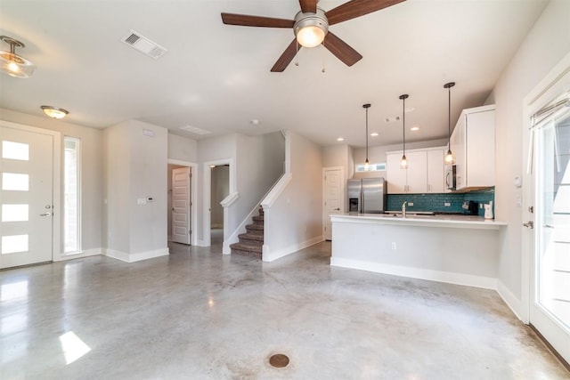 1904 Cleese Dr Unit 172, Austin, TX 78741 - kitchen featuring appliances with stainless steel finishes, concrete floors, a peninsula, tasteful backsplash, and white cabinets