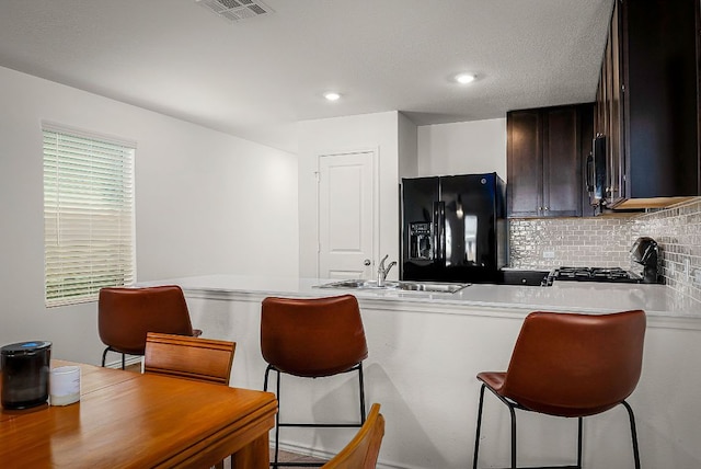 175 Amber Gln, Maxwell, TX 78656 - kitchen featuring black refrigerator with ice dispenser, stove, a breakfast bar, light countertops, and tasteful backsplash