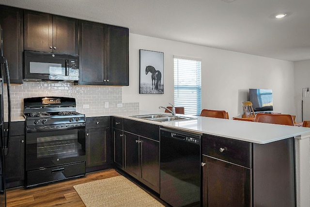 175 Amber Gln, Maxwell, TX 78656 - kitchen featuring black appliances, a peninsula, dark wood-style flooring, backsplash, and light countertops