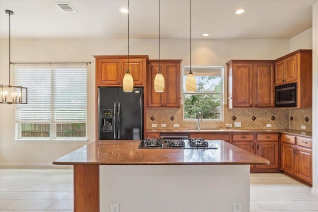 102 Country View Way, Cedar Park, TX 78613 - kitchen with black refrigerator with ice dispenser, gas stovetop, built in microwave, brown cabinetry, and a kitchen island
