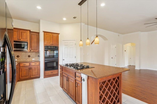 102 Country View Way, Cedar Park, TX 78613 - kitchen with black appliances, arched walkways, brown cabinetry, tasteful backsplash, and stone counters