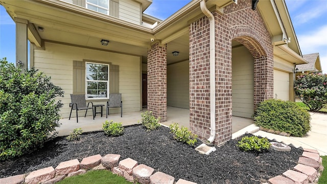 201 Garcitas Creek Ln, Hutto, TX 78634 - view of exterior entry featuring brick siding, a porch, and an attached garage