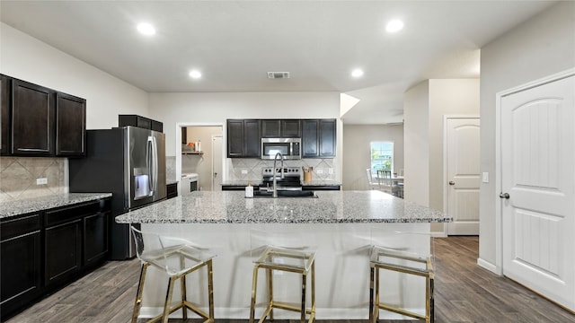 201 Garcitas Creek Ln, Hutto, TX 78634 - kitchen featuring appliances with stainless steel finishes, a breakfast bar, backsplash, dark wood-type flooring, and recessed lighting