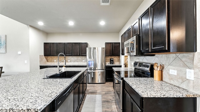 201 Garcitas Creek Ln, Hutto, TX 78634 - kitchen featuring stainless steel appliances, decorative backsplash, light wood finished floors, light stone counters, and recessed lighting