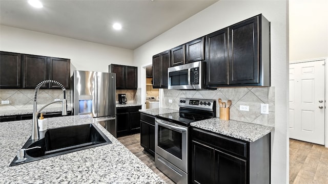 201 Garcitas Creek Ln, Hutto, TX 78634 - kitchen featuring appliances with stainless steel finishes, light wood-style floors, decorative backsplash, light stone countertops, and recessed lighting