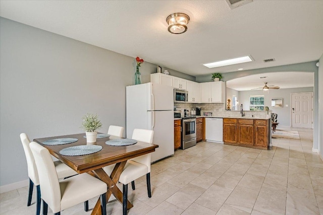 215 Peaceful Haven Way, Hutto, TX 78634 - kitchen featuring stainless steel appliances, a peninsula, ceiling fan, light countertops, and backsplash