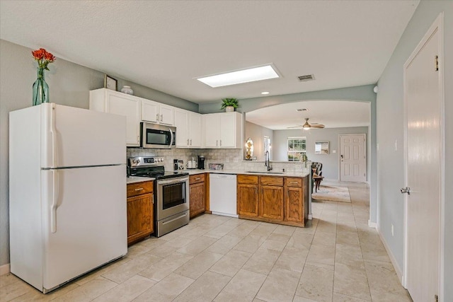 215 Peaceful Haven Way, Hutto, TX 78634 - kitchen with appliances with stainless steel finishes, a peninsula, arched walkways, decorative backsplash, and light countertops