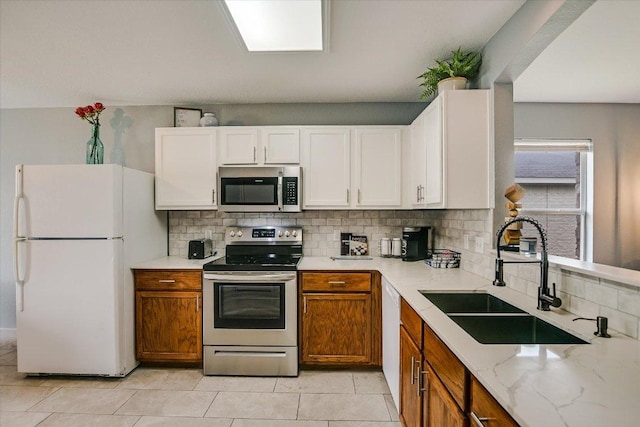 215 Peaceful Haven Way, Hutto, TX 78634 - kitchen featuring stainless steel appliances, decorative backsplash, light stone countertops, white cabinetry, and brown cabinets