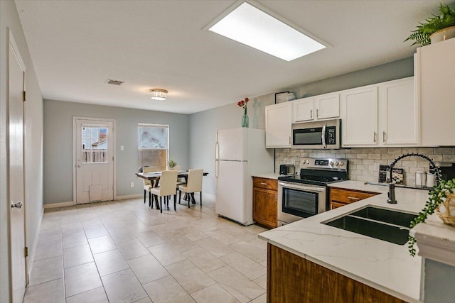 215 Peaceful Haven Way, Hutto, TX 78634 - kitchen with stainless steel appliances, decorative backsplash, light stone countertops, white cabinets, and light tile patterned floors