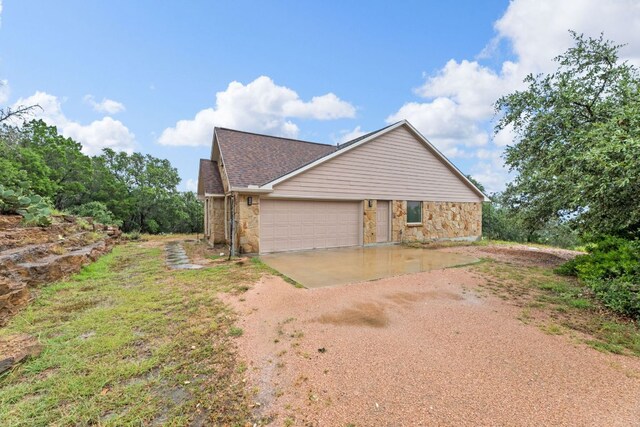 851 Stone Mountain Dr, Marble Falls, TX 78654 - view of property exterior featuring driveway, stone siding, roof with shingles, and a garage