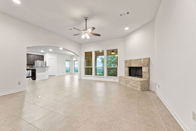 851 Stone Mountain Dr, Marble Falls, TX 78654 - unfurnished living room with ceiling fan, light tile patterned floors, arched walkways, a stone fireplace, and recessed lighting