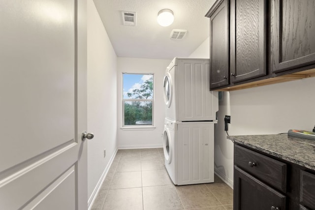 851 Stone Mountain Dr, Marble Falls, TX 78654 - laundry area featuring stacked washer / drying machine, cabinet space, and light tile patterned floors