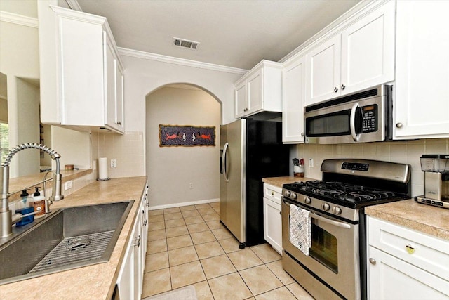 7312 Meador Ave, Austin, TX 78752 - kitchen with stainless steel appliances, ornamental molding, white cabinets, light countertops, and tasteful backsplash
