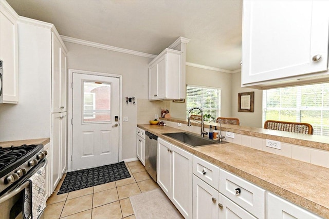 7312 Meador Ave, Austin, TX 78752 - kitchen with stainless steel appliances, white cabinetry, crown molding, light countertops, and light tile patterned floors